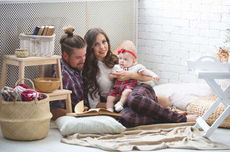Happy young family mother, father and daughter playing on carpet at home.の写真素材
