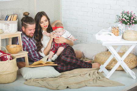 Happy young family mother, father and daughter playing on carpet at home.の写真素材