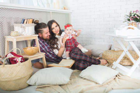 Happy young family mother, father and daughter playing on carpet at home.の写真素材