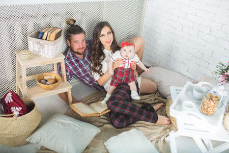 Happy young family mother, father and daughter playing on carpet at home.の写真素材