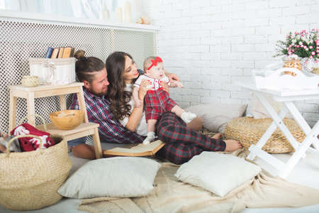 Happy young family mother, father and daughter playing on carpet at home.の写真素材