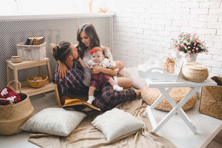 Happy young family mother, father and daughter playing on carpet at home.の写真素材