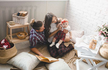 Happy young family mother, father and daughter playing on carpet at home.
