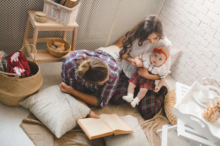 Happy young family mother, father and daughter playing on carpet at home.の写真素材