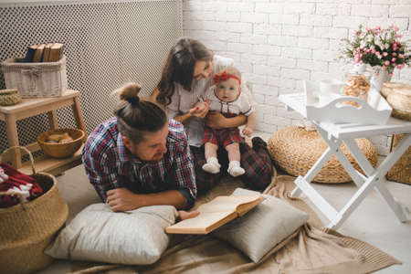 Happy young family mother, father and daughter playing on carpet at home.の写真素材