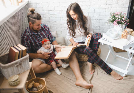 Happy young family mother, father and daughter playing on carpet at home.の写真素材