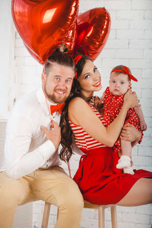 Happy young family mother, father and daughter posing in studio.の写真素材