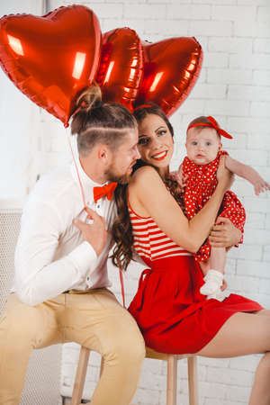 Happy young family mother, father and daughter posing in studio.の写真素材