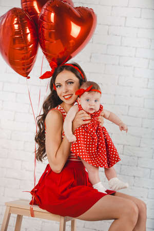 Happy young family mother and daughter posing in studio.の写真素材