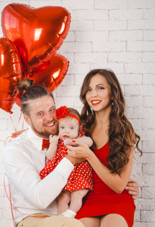 Happy young family mother, father and daughter posing in studio.の写真素材