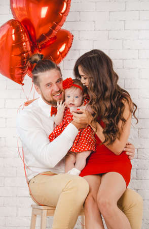 Happy young family mother, father and daughter posing in studio.の写真素材