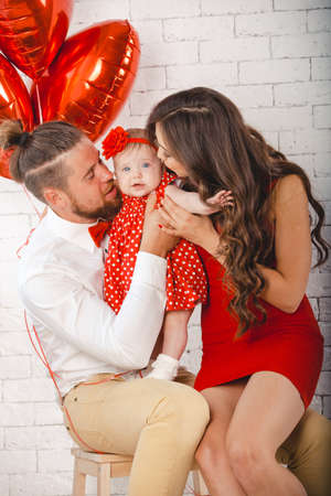 Happy young family mother, father and daughter posing in studio.の写真素材