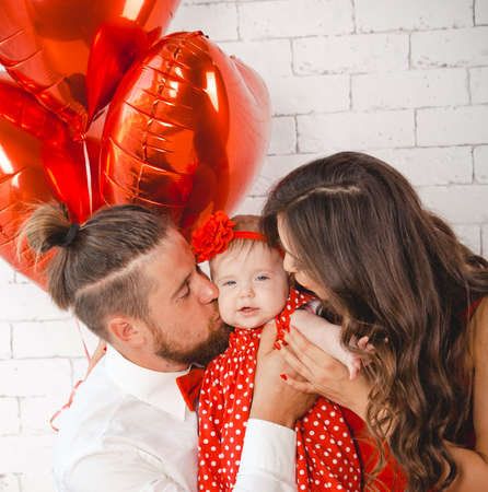 Happy young family mother, father and daughter posing in studio.の写真素材