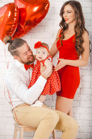 Happy young family mother, father and daughter posing in studio.の写真素材