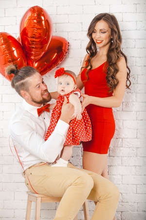 Happy young family mother, father and daughter posing in studio.の写真素材