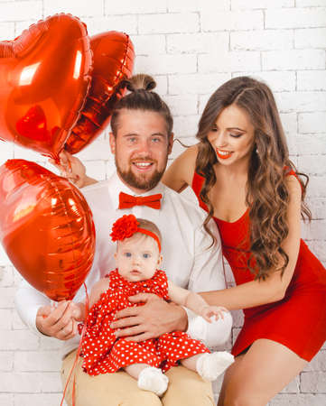 Happy young family mother, father and daughter posing in studio.の写真素材
