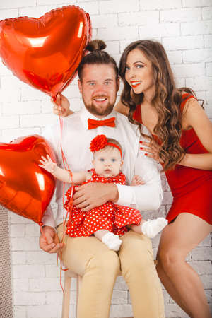 Happy young family mother, father and daughter posing in studio.の写真素材