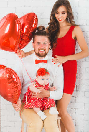 Happy young family mother, father and daughter posing in studio.の写真素材
