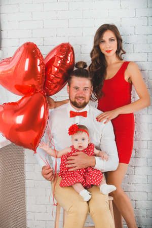 Happy young family mother, father and daughter posing in studio.の写真素材