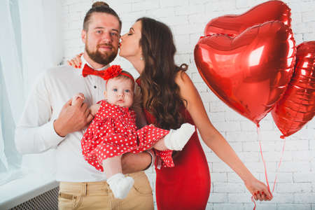 Happy young family mother, father and daughter posing in studio.の写真素材