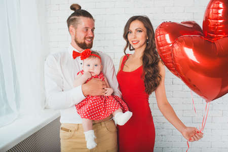 Happy young family mother, father and daughter posing in studio.の写真素材