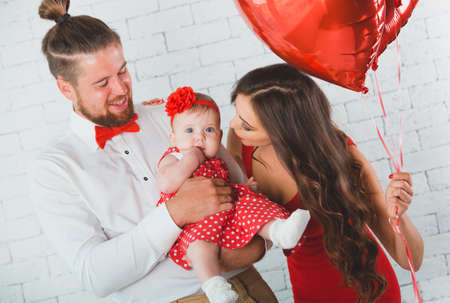 Happy young family mother, father and daughter posing in studio.の写真素材