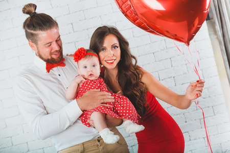 Happy young family mother, father and daughter posing in studio.の写真素材