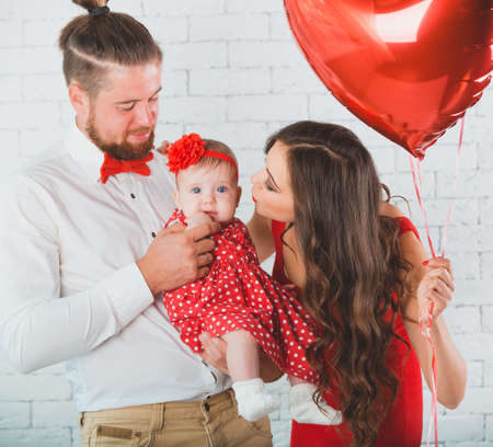Happy young family mother, father and daughter posing in studio.の写真素材