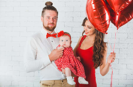 Happy young family mother, father and daughter posing in studio.の写真素材