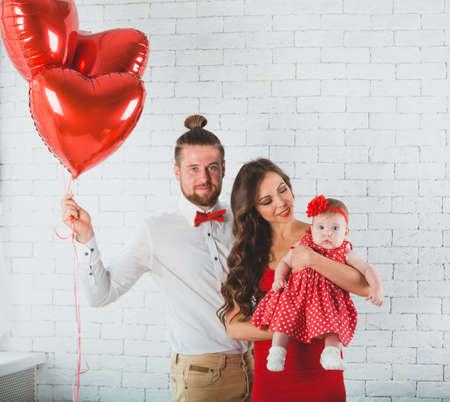 Happy young family mother, father and daughter posing in studio.の写真素材