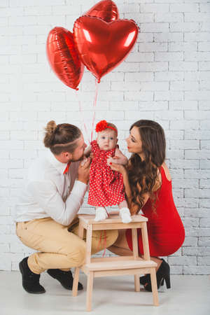 Happy young family mother, father and daughter posing in studio.の写真素材