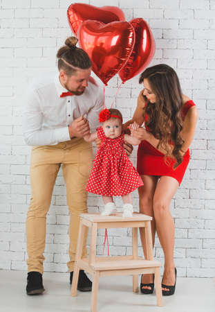 Happy young family mother, father and daughter posing in studio.の写真素材