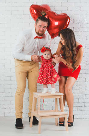 Happy young family mother, father and daughter posing in studio.の写真素材