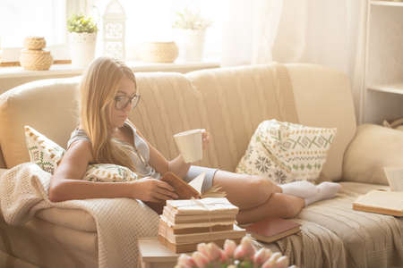 Young woman reading book at homeの写真素材