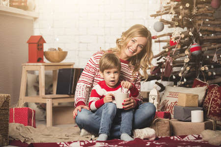 Portrait of happy mother and son on the background of the Christmas tree in new year room. The idea for postcardsの写真素材
