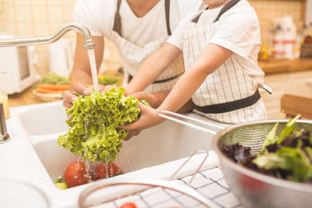 Man and boy washing vegetables before eatingの写真素材