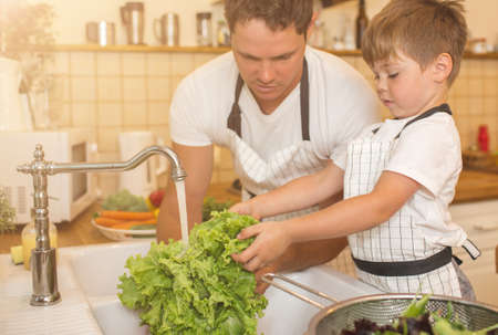 Man and boy washing vegetables before eatingの写真素材
