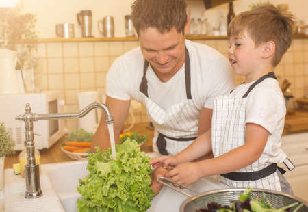 Man and boy washing vegetables before eatingの写真素材