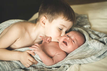 Two brothers are lying on a knitted coverletの写真素材
