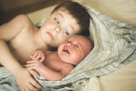 Two brothers are lying on a knitted coverletの写真素材