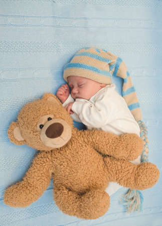 newborn baby laying with teddy bear on blanketの写真素材