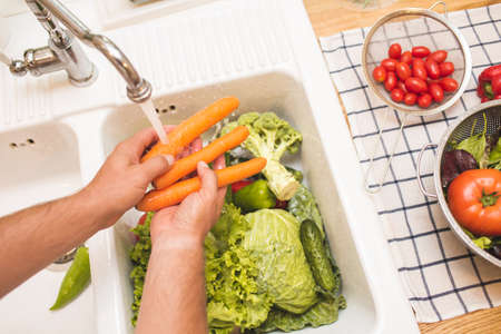Man washing carrots before eatingの写真素材