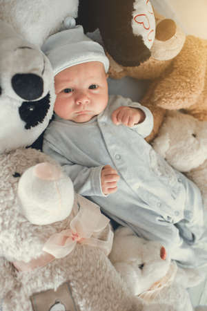 newborn baby laying with five teddy bears on blanketの写真素材