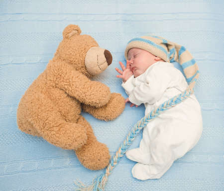 newborn baby laying with teddy bear on blanketの写真素材
