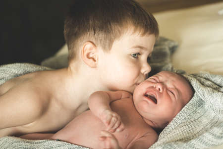 Two brothers are lying on a knitted coverletの写真素材