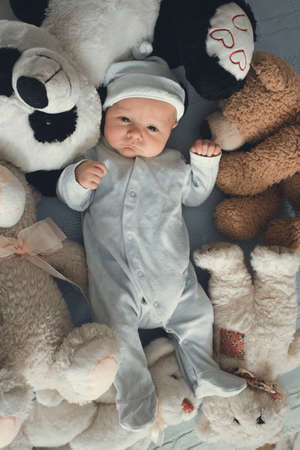 newborn baby laying with five teddy bears on blanketの写真素材