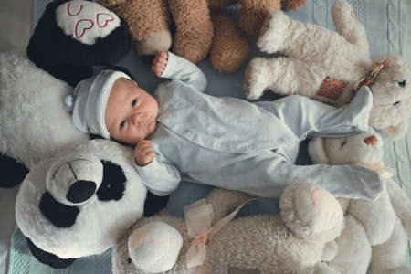 newborn baby laying with five teddy bears on blanketの写真素材