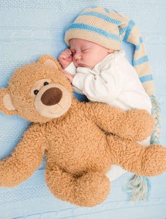 newborn baby laying with teddy bear on blanketの写真素材