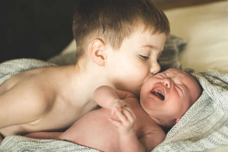 Two brothers are lying on a knitted coverletの写真素材