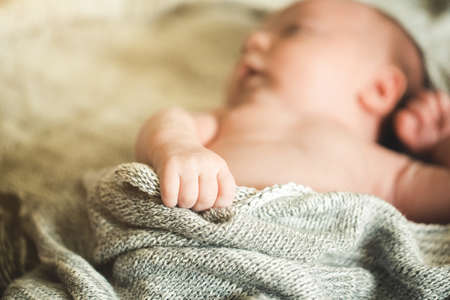 The childs hands hold a knitted blanket